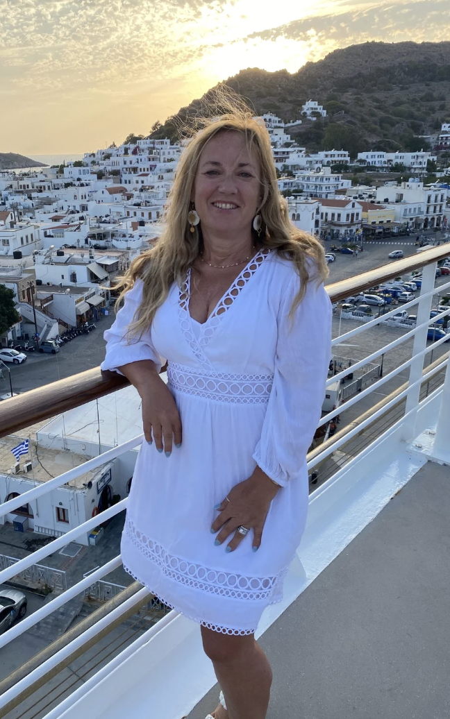 A photo of Rona on top of a small cruise ship deck with a view of white buildings in the background.