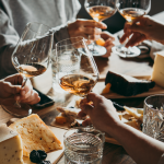 Cultural and Culinary Travel People cheersing wine glasses over a table full of food.
